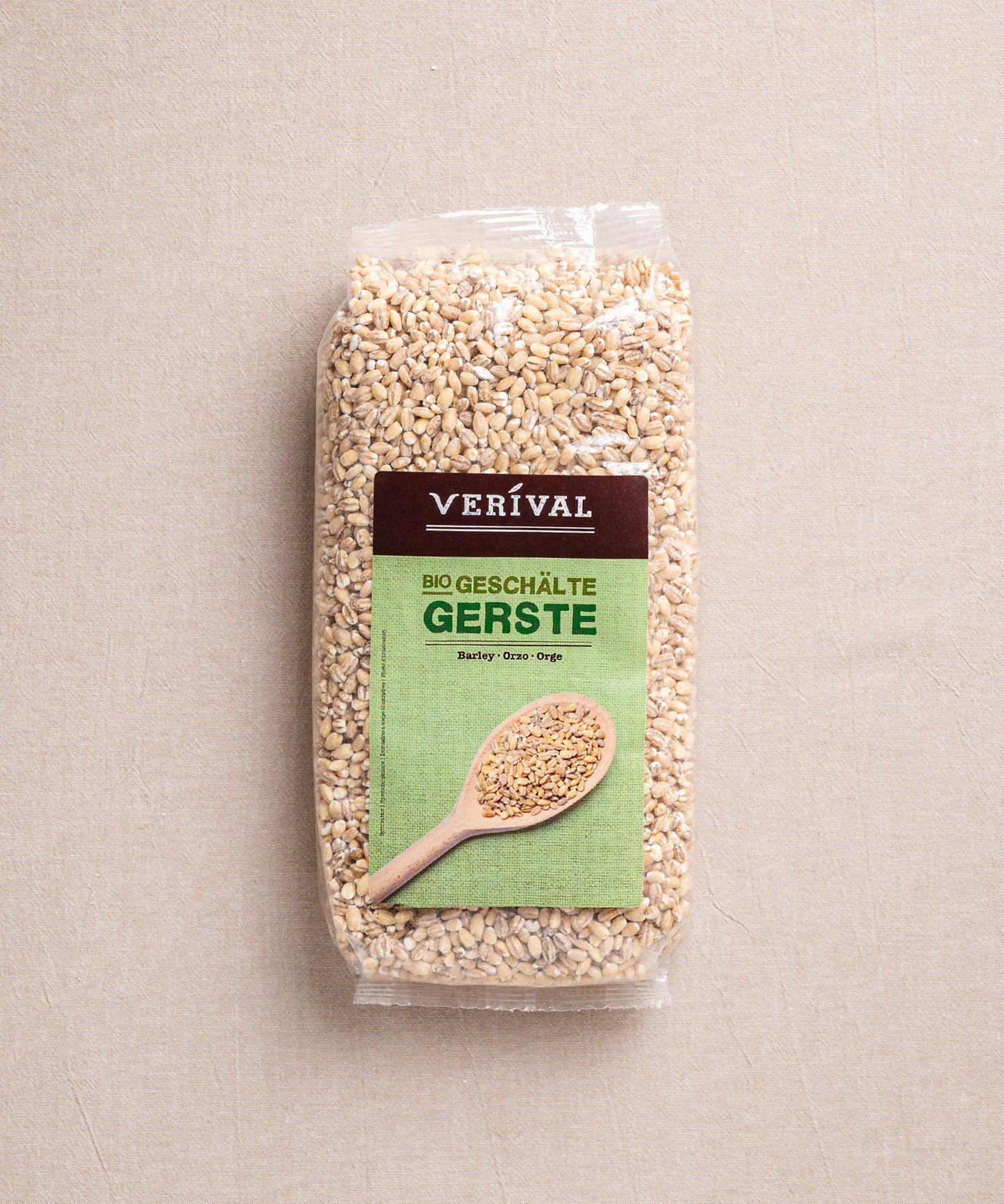 Eine Packung ballaststoffreiche Bio-Gerste der Verival Bio GmbH liegt auf einem beigen Untergrund. Das Etikett zeigt einen Holzlöffel mit Perlgraupenkörnern und betont damit die natürliche cholesterinsenkende Wirkung.