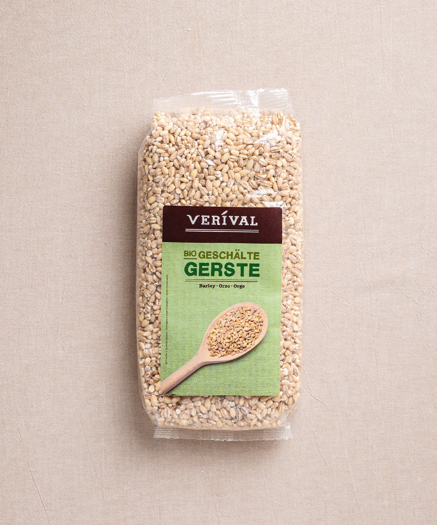 Eine Packung ballaststoffreiche Bio-Gerste der Verival Bio GmbH liegt auf einem beigen Untergrund. Das Etikett zeigt einen Holzlöffel mit Perlgraupenkörnern und betont damit die natürliche cholesterinsenkende Wirkung.