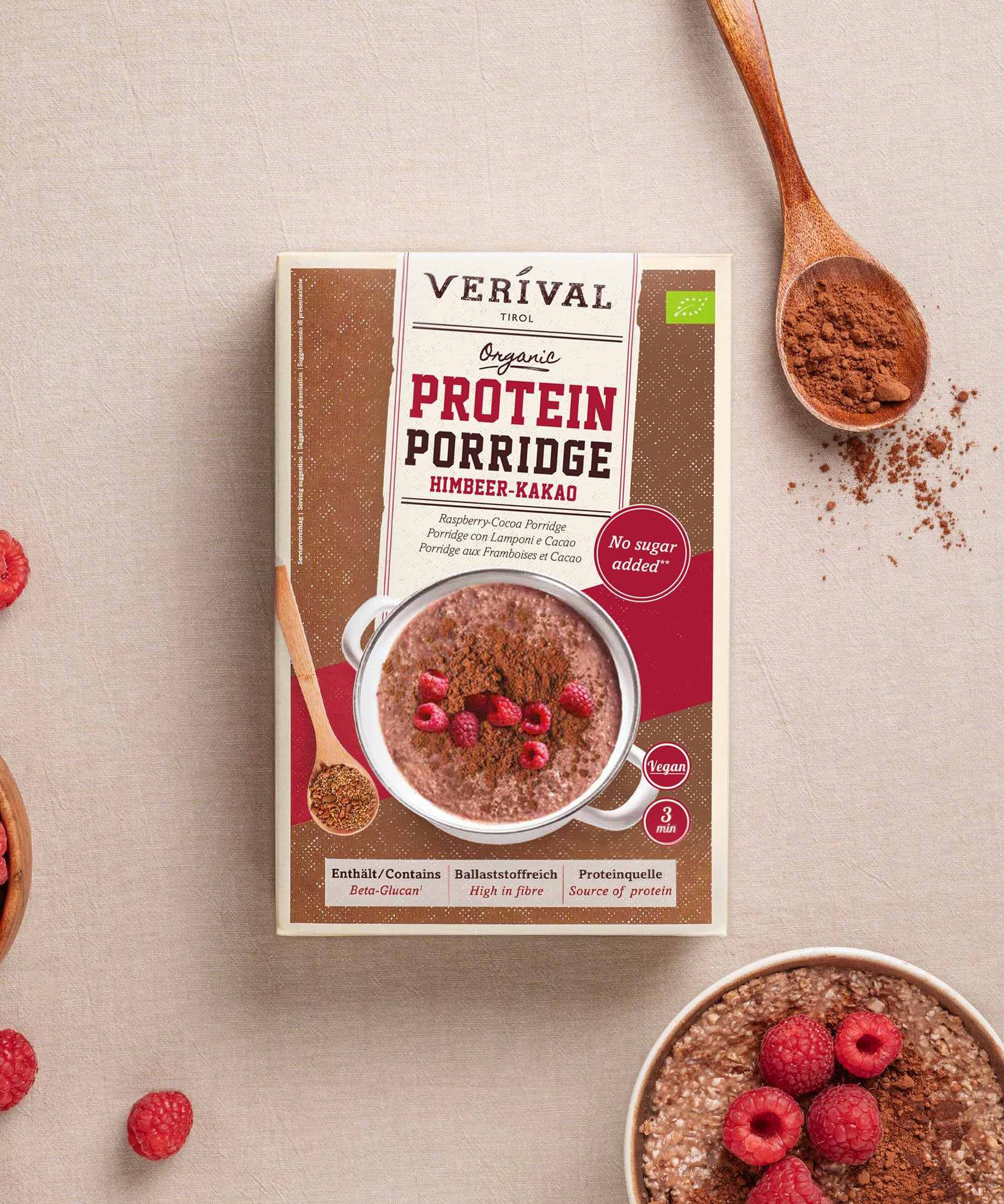 Schachtel Protein Porridge Himbeer-Kakao der Verival Bio GmbH, ein veganes Power-Frühstück mit Himbeeren, Kakaopulver und einem Holzlöffel auf Beige – perfekt als Sport Porridge, um Energie für den Tag zu tanken.